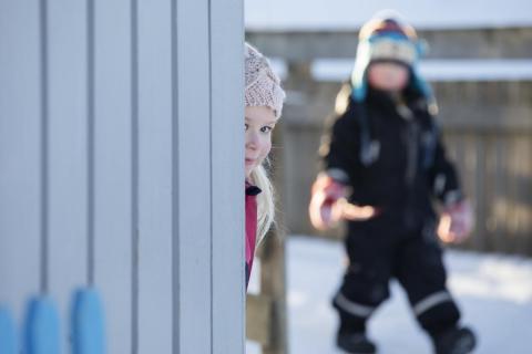 Jente som kikker rundt et hushjørne